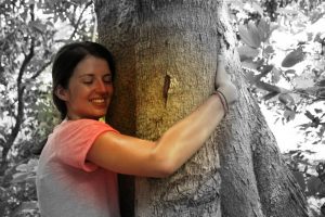 Jeune femme entourant un arbre de ses bras et recevant ainsi l'énergie de l'arbre