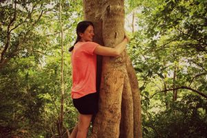 Jeune femme faisant un câlin à un arbre. Plan large